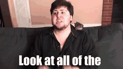 a man with a beard is sitting on a couch with a bird on his shoulder .