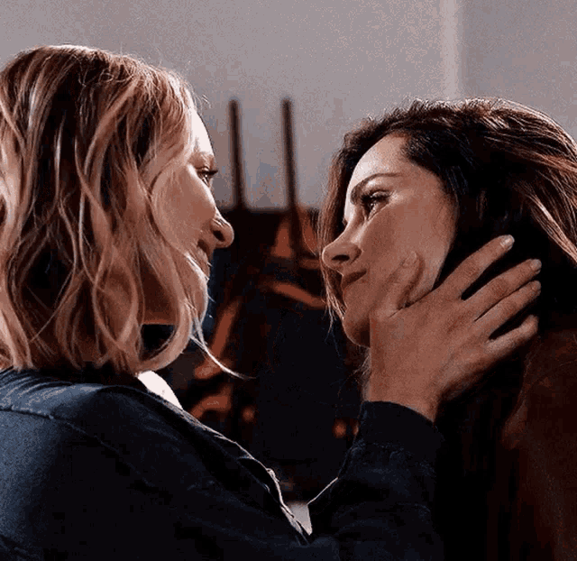 two women are touching each other 's faces in a close up