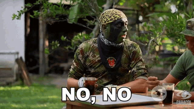a man with a bandana on his head is sitting at a table and says " no no "