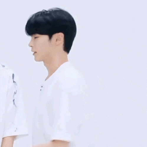 a young man wearing a white t-shirt with korean writing on it is laughing .