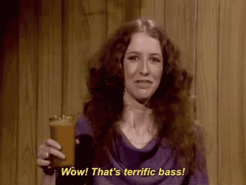 a woman with long red hair is holding a glass and saying wow that 's terrific bass .
