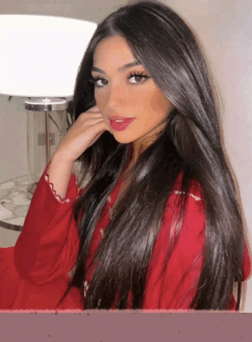 a woman with long dark hair is wearing a red top