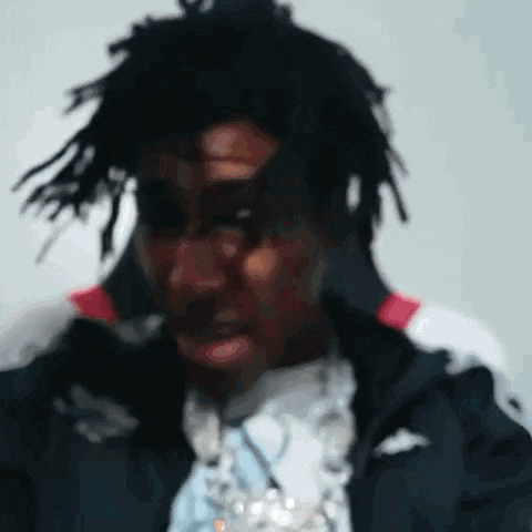 a close up of a man 's face with dreadlocks and a jacket on .