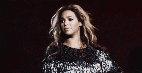 a woman is standing on a stage wearing a sequined top and making a funny face .