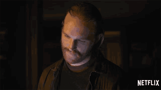 a man with a beard is looking at the camera with a netflix logo in the corner