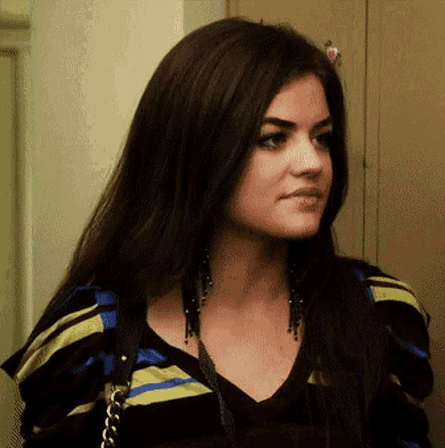 a woman with long dark hair is wearing a striped shirt and earrings