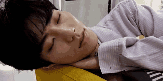 a young man in a striped shirt is sleeping on a yellow couch .