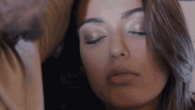 a woman with her eyes closed is laying on a couch .