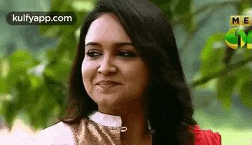 a woman is smiling and looking at the camera while standing in a park .