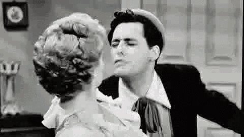a black and white photo of a man and a woman kissing .