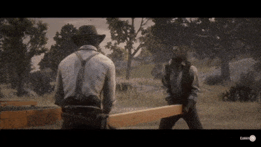 a man in a cowboy hat is standing next to another man holding a large piece of wood ..