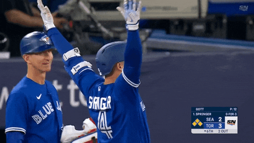 two blue jays players high five each other during a baseball game