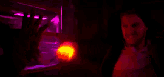 a man is standing in a dark room with a red light shining on him .