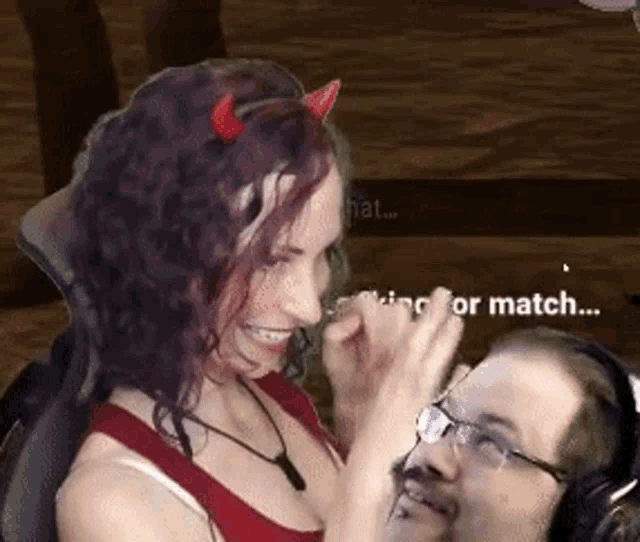 a woman with devil horns is sitting next to a man wearing headphones .