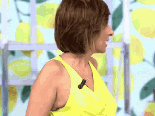 a woman wearing a yellow tank top with a microphone on her neck