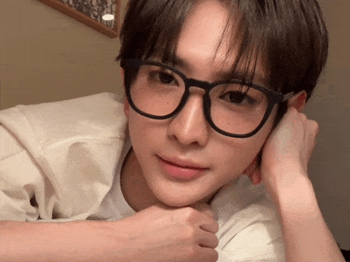 a young man wearing glasses looks at the camera