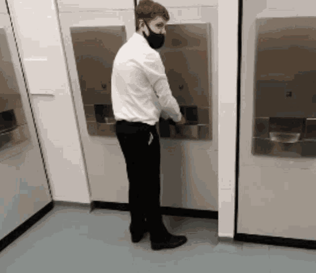 a man wearing a mask is standing in front of an atm