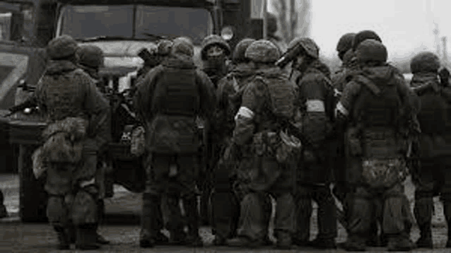 a group of soldiers are standing in a huddle in front of a truck .