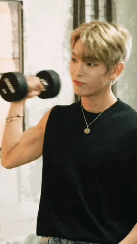 a man in a black tank top is lifting a dumbbell