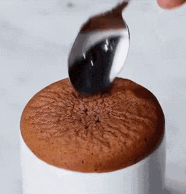 a person is using a spoon to scoop a chocolate cake out of a bowl .