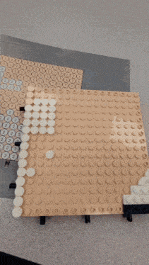 a person 's hand is holding a piece of lego that has numbers 1 through 2 on it