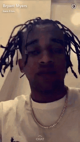 a man with dreadlocks is wearing a white shirt