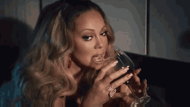 a woman is drinking a glass of wine while wearing a ring .