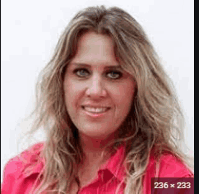 a woman in a red shirt is smiling for the camera .