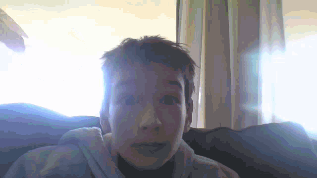 a man with a surprised look on his face is sitting in front of a window