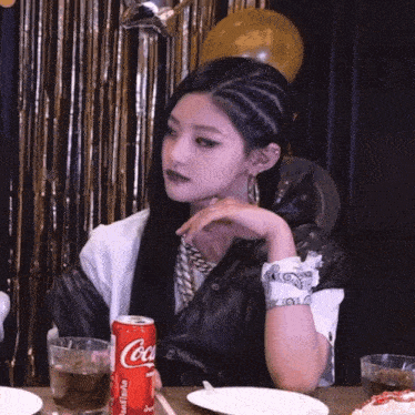 a woman sits at a table with a can of coca cola in her hand