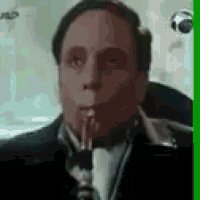 a man in a suit and tie is smoking a pipe .