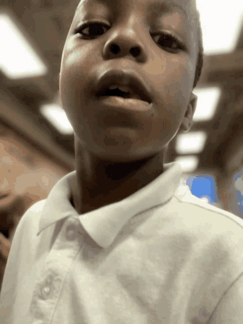 a young boy wearing a white shirt is looking at the camera