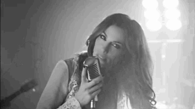 a woman is holding a microphone in her hand and singing into it .