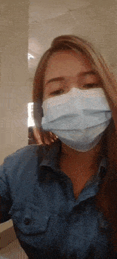 a woman wearing a denim shirt and a blue face mask