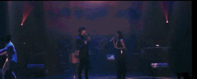 a young man is singing into a microphone on a stage .