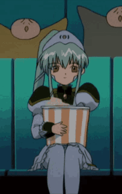 a girl with green hair is sitting in a theater holding a striped popcorn bucket