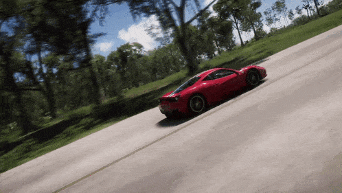 a red sports car is driving down a road surrounded by trees