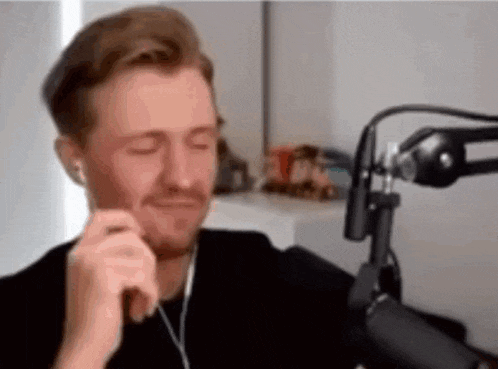 a man is sitting in front of a microphone wearing headphones and a black shirt .