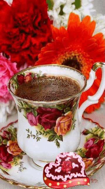 a cup of coffee on a saucer next to flowers