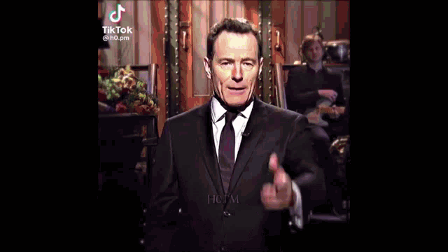 a man in a suit and tie is standing in front of a keyboard in a video .