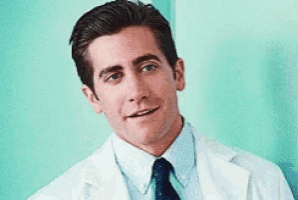 a man in a lab coat and tie is smiling .