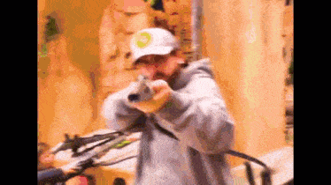 a man wearing a hat is holding a gun and pointing it at the camera .
