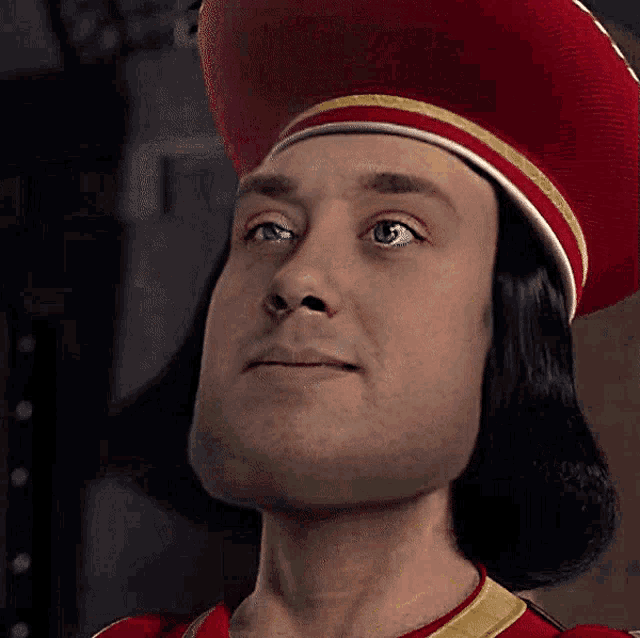 a close up of a man wearing a red hat with gold trim