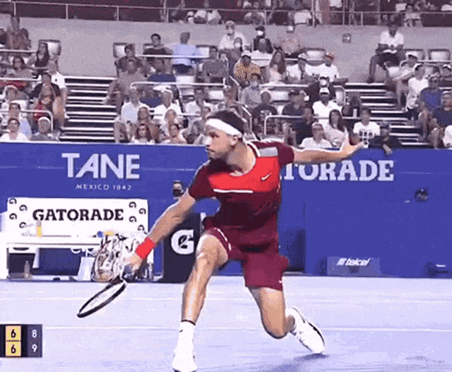 a tennis player is running with a tennis racquet in front of a banner that says gatorade