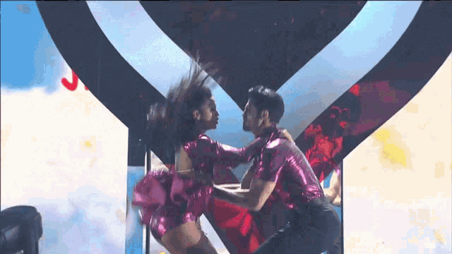 a man and a woman are dancing in front of a heart shaped background