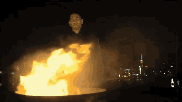 a man is standing in front of a fire