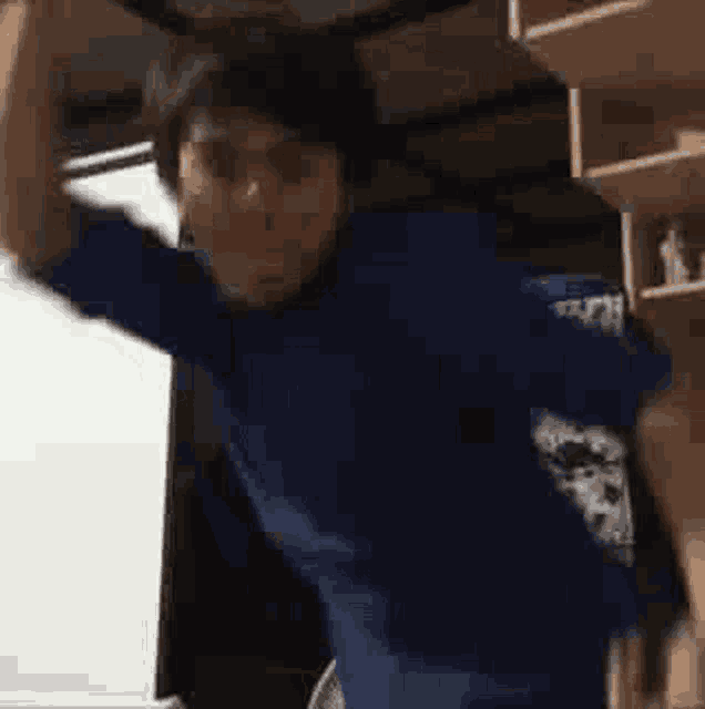 a man in a blue shirt is dancing in a room with his arms in the air .