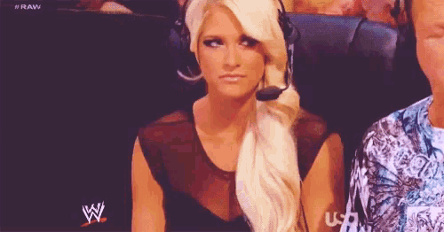 a woman wearing a headset is sitting in front of a wwe logo