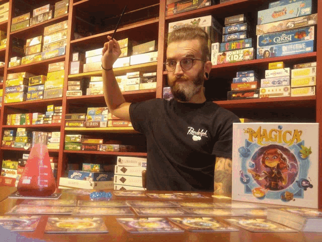 a man stands in front of a shelf full of board games including ghost