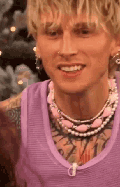 a close up of a man wearing a purple tank top and pearls .